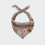 CLOUD7_ Das Hundehalstuch Bandana LTTL Blossoms ist ein dreieckiges Halstuch für Haustiere mit einem Krawattenknoten, einem Blumenmuster in Rosa, Orange und Grün und einem braunen Lederaufnäher. Ein unverzichtbares Hund-Accessoire für stilvolle Welpen. Einfarbig weißer Hintergrund.
