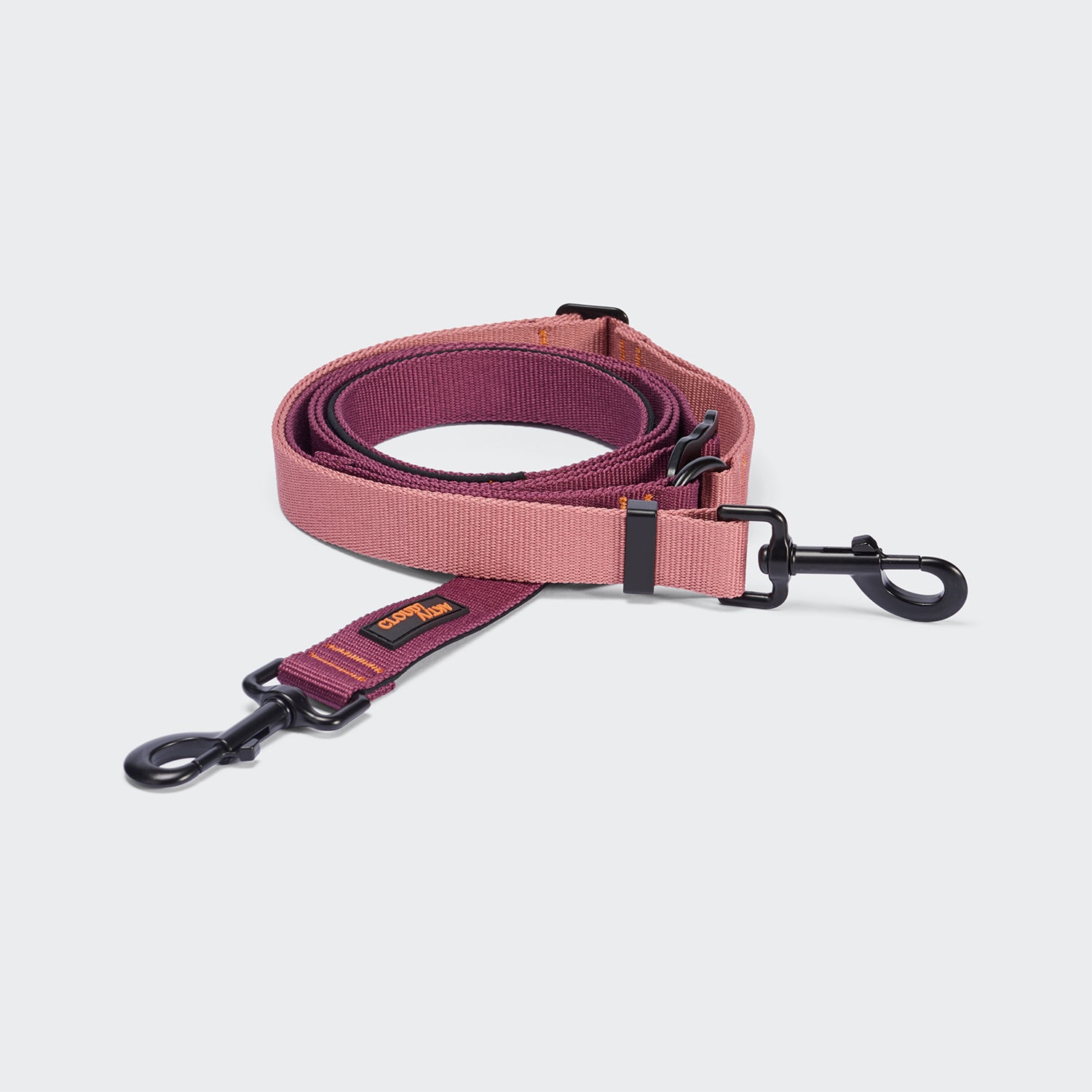 CLOUD7_ Eine aufgerollte L-1 Freihandleine AKTIV in den Farben Aubergine/Soft Rose – diese zweifarbige Hundeleine ist in Rosa und Burgunderrot gehalten und verfügt an beiden Enden über schwarze Metallkarabiner sowie ein kleines, rechteckiges Etikett in Orange und Braun, das in der Nähe eines Karabiners angebracht ist. Die längenverstellbare Hundeleine ist für eine individuelle Längenanpassung ausgelegt.