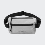 CLOUD7_ Die Gürteltasche AKTIV Reflective hat hellgraues, reflektierendes Material, einen schwarzen, verstellbaren Riemen, zwei Reißverschlussfächer und CLOUD7 ART/LY in schwarzer Schrift auf der Vorderseite.