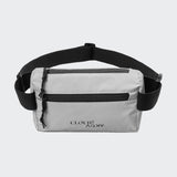 CLOUD7_ Die Gürteltasche AKTIV Reflective hat hellgraues, reflektierendes Material, einen schwarzen, verstellbaren Riemen, zwei Reißverschlussfächer und CLOUD7 ART/LY in schwarzer Schrift auf der Vorderseite.