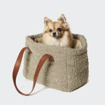 CLOUD7_ Ein kleiner flauschiger Hund sitzt in der Hundetasche Verona Wool Beige - einer weichen, strukturierten beigen Tasche mit braunen Ledergriffen - und blickt nach vorne auf einen schlichten weißen Hintergrund.