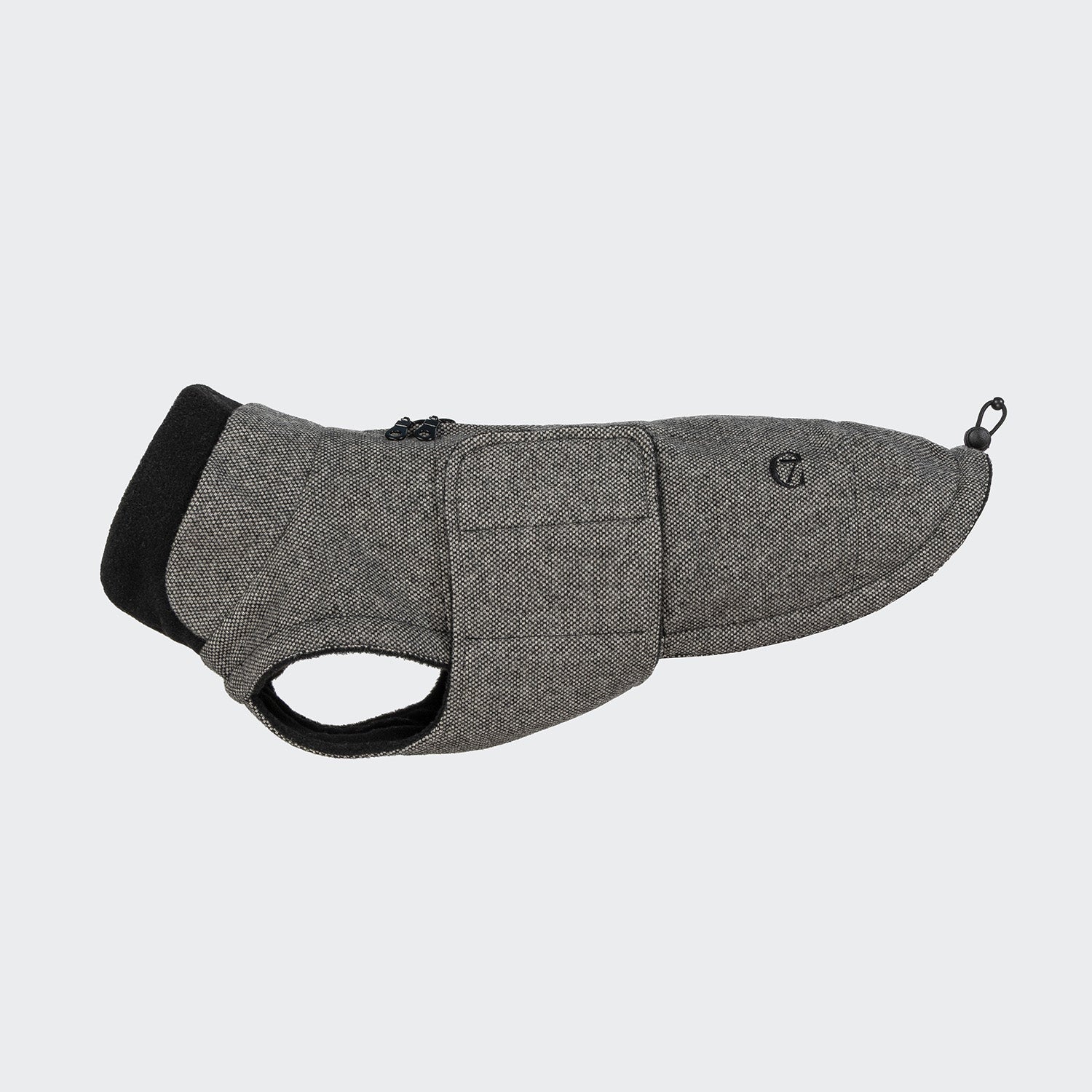 CLOUD7_ Der Hundemantel Dackel Brooklyn Tweed Black ist ein grauer, strukturierter Hundemantel mit schwarzem Besatz, einem Reißverschluss auf der Rückseite und einem Clip in der Nähe der Rute. Er ist so konzipiert, dass er eng anliegt und mit Riemen unter dem Körper Ihres Dackels befestigt werden kann.