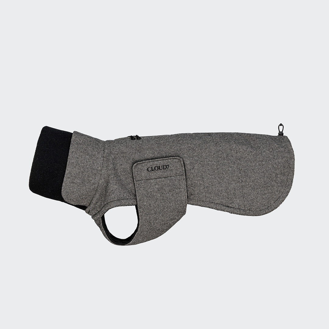 CLOUD7_ Ein grauer, wollähnlicher Windhundmantel Brooklyn Long Tweed Black mit schwarzem Halsbesatz, Klettverschluss am Bauch für optimierte Passform, Gurtloch, flach gelegt auf einem einfarbigen hellen Hintergrund dargestellt.