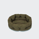 CLOUD7_ Das Hundekissen Lazy Canvas Olive ist ein rundes, olivgrünes Haustierbett mit gepolsterten Seiten und Boden, das auf einem schlichten hellgrauen Hintergrund abgebildet ist.