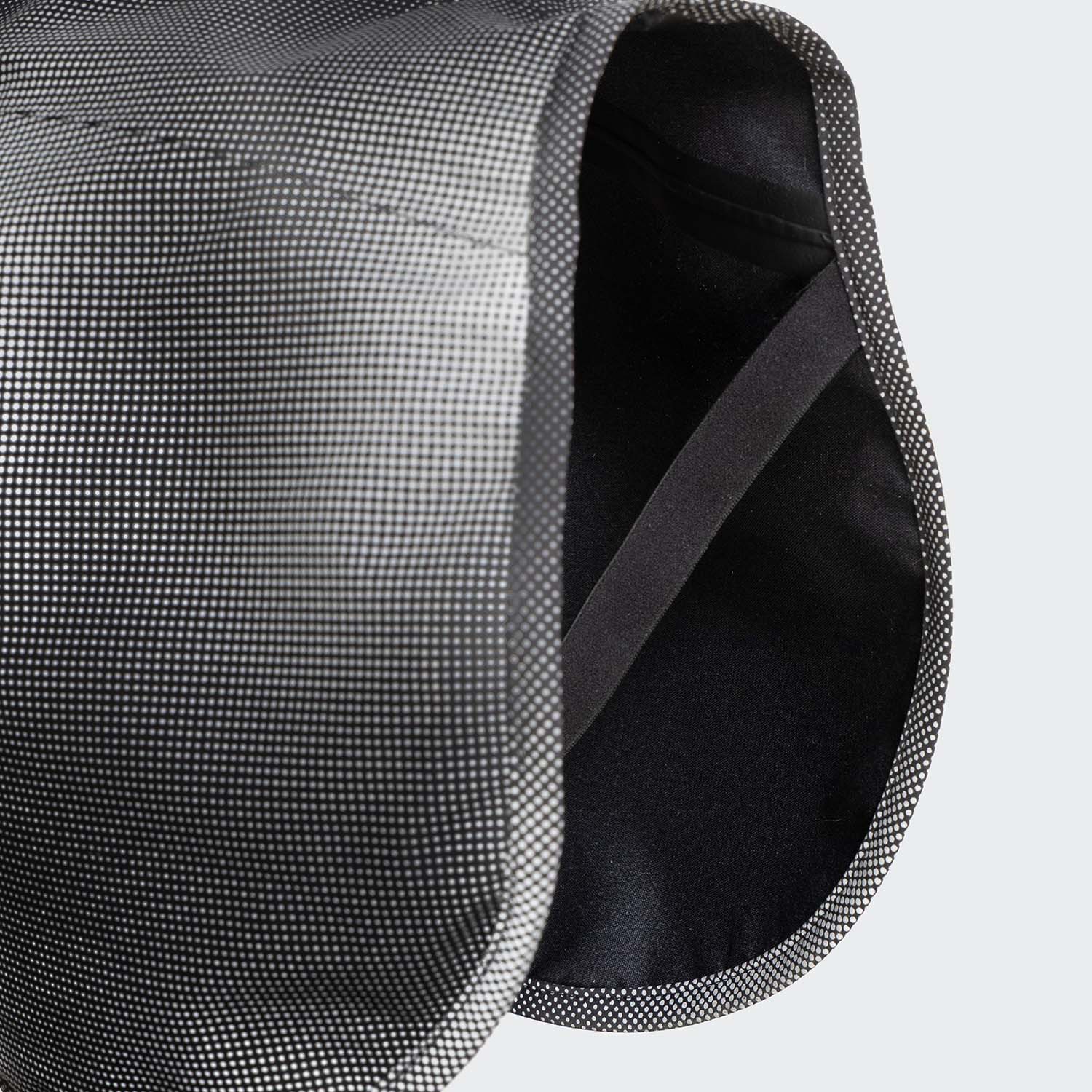 CLOUD7_ Nahaufnahme eines strukturierten, geschwungenen grauen und schwarzen Stoffes mit Punktmuster und schwarzem Innenfutter, möglicherweise Teil eines Kleidungsstücks oder einer Tasche.