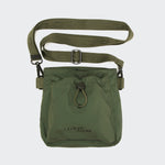 CLOUD7_ Der Leckerlibeutel AKTIV Olive ist eine olivgrüne Crossbody-Tasche mit einem verstellbaren Riemen, einer Vordertasche mit Kordelzug und einem CLOUD7-Branding auf der Vorderseite. Sie ist Teil der AKTIV Kollektion und wird vor einem schlichten, hellen Hintergrund gezeigt.