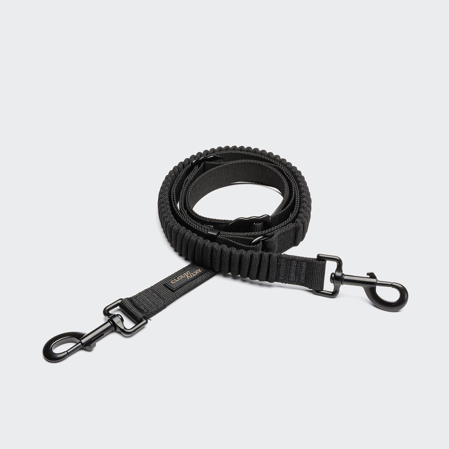 CLOUD7_ Die L-2 Jogging-Leine AKTIV Black, eine aufgerollte Hundeleine mit Stoßdämpfung und Metallclips an beiden Enden, ist auf hellgrauem Hintergrund abgebildet. Sie verfügt über einen gepolsterten Griff, robuste Nähte und eignet sich für aktive Hundebesitzer.