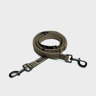 CLOUD7_ Die L-2 Jogging-Leine AKTIV Olive ist eine stoßdämpfende, olivgrüne Nylon-Hundeleine mit schwarzen Metallclips - perfekt für freihändiges Gassi gehen oder Joggen, präsentiert auf einem hellgrauen Hintergrund.