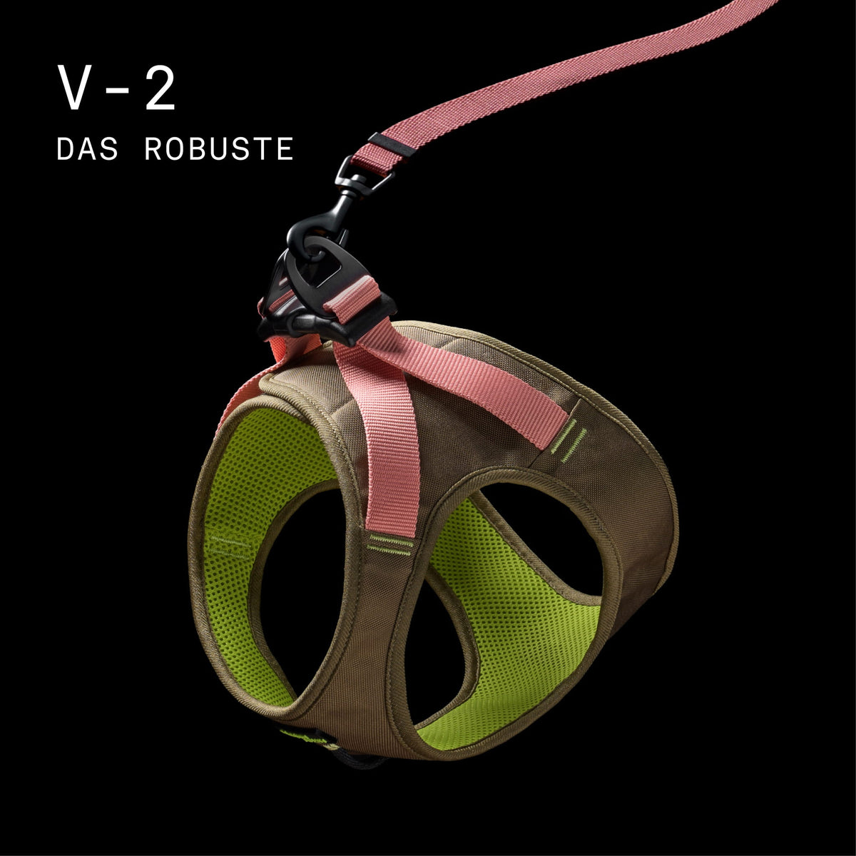 CLOUD7_ Ein braun-grünes Hundegeschirr mit rosa Riemen und einer dazu passenden Leine, dargestellt vor schwarzem Hintergrund. Der Text lautet: „V-2 DAS ROBUSTE“.