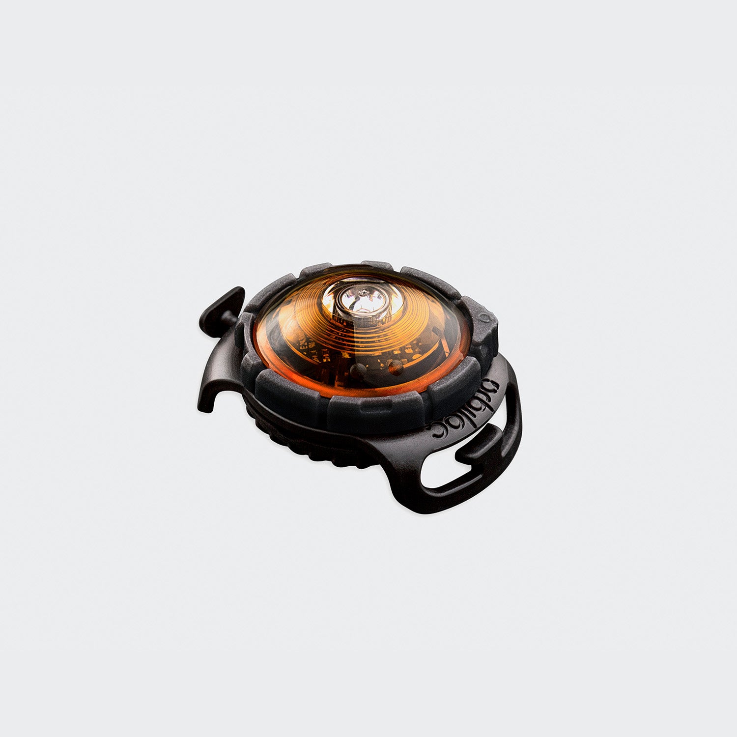 CLOUD7_ Das Orbiloc Dog Dual™ Sicherheitslicht Orange ist ein kleines, rundes, gelbes Sicherheitslicht mit einem schwarzen Gummigehäuse und seitlichen Befestigungsschlaufen, das sich leicht an Kleidung, Ausrüstung oder LED-Hundehalsbändern für Haustiere befestigen lässt.