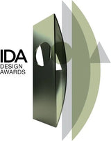 CLOUD7_ Das Logo der IDA Design Awards mit einer metallisch anmutenden, abstrakten geometrischen Form sowie übereinanderliegenden, durchscheinenden grünen Bögen und Dreiecken, platziert neben dem Schriftzug „IDA DESIGN AWARDS“ auf weißem Hintergrund.