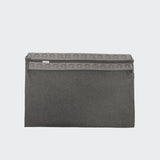 CLOUD7_ Der Outdoor Wechselbezug Siesta Light Graphite ist eine graue Laptoptasche aus Stoff mit Klappenverschluss und geometrischem Muster, mit einem kleinen rechteckigen Etikett auf der linken oberen Seite. Hergestellt aus leicht zu reinigendem, maschinenwaschbarem, wasserabweisendem Bezug. Einfarbig weißer Hintergrund.