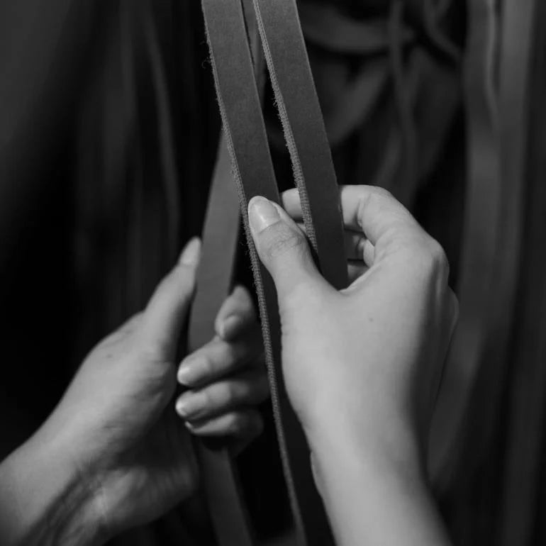 Close up of hands sorting cut strands of leather 