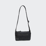 CLOUD7_ Die RESC7UE Leckerlitasche Plush Anthra ist eine kleine, rechteckige, strukturierte schwarze Crossbody-Tasche mit einem verstellbaren Riemen, einer Reißverschlusstasche auf der Vorderseite und einem Reißverschluss mit rundem Etikett, der vor einem einfarbigen hellgrauen Hintergrund abgebildet ist.